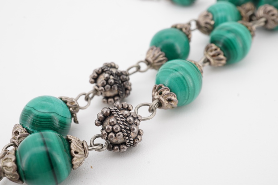 An Arts & Crafts silver and malachite necklace, early 20th century composite, the front composed of malachite beads in silver wire work mounts, suspending a green hardstone pendant in a floral silver border, necklace len